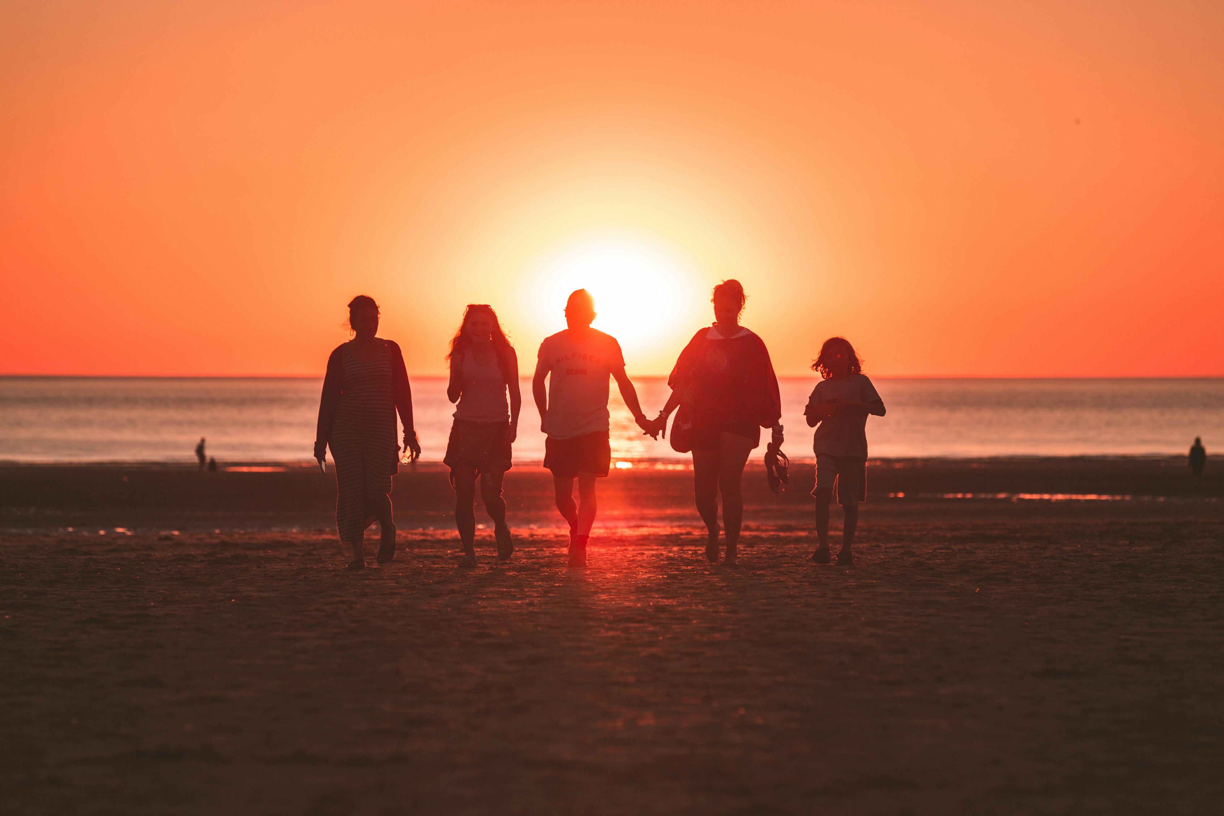 Familia caminando por la playa al atardecer