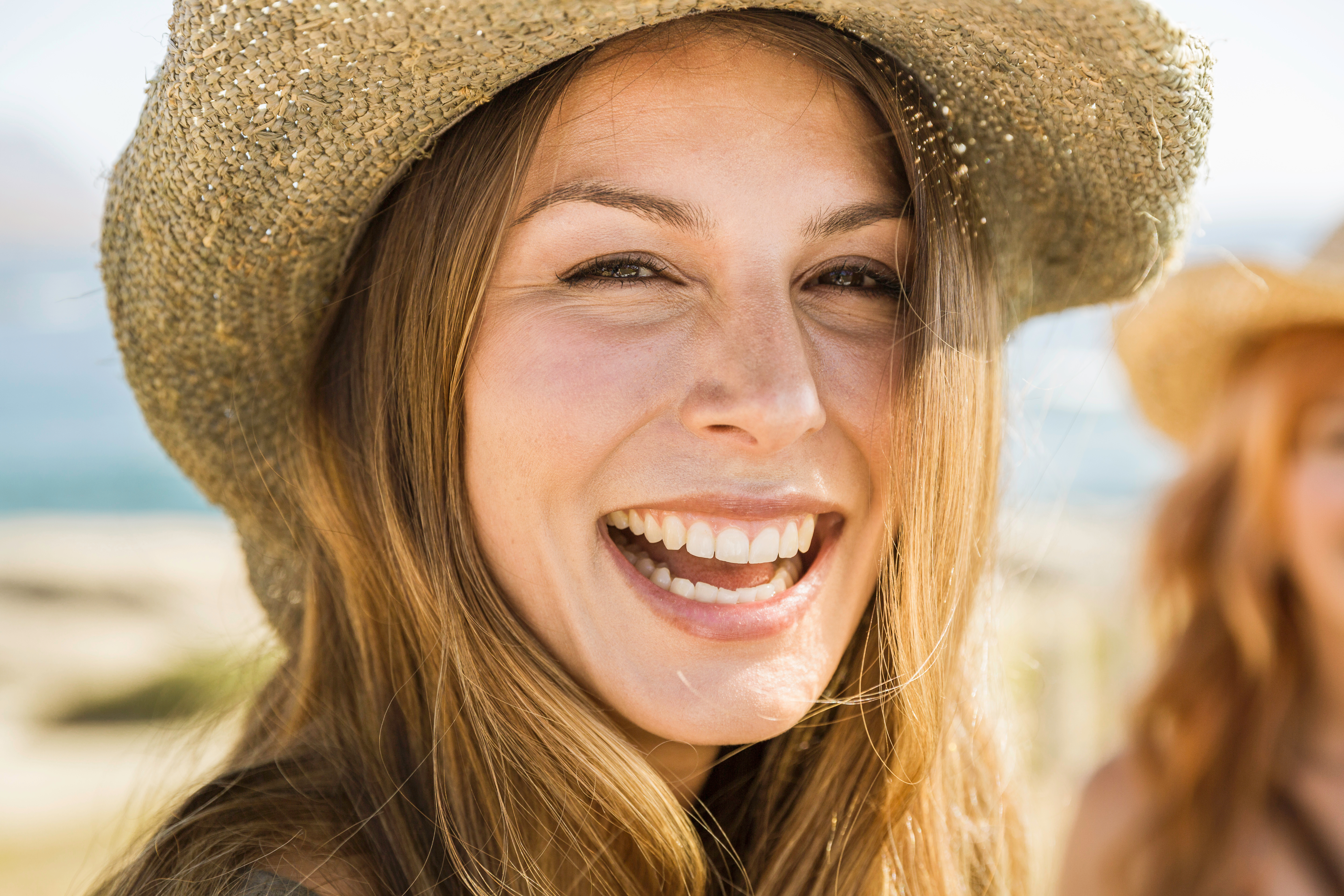 Mujer con sombrero riendo en la playa